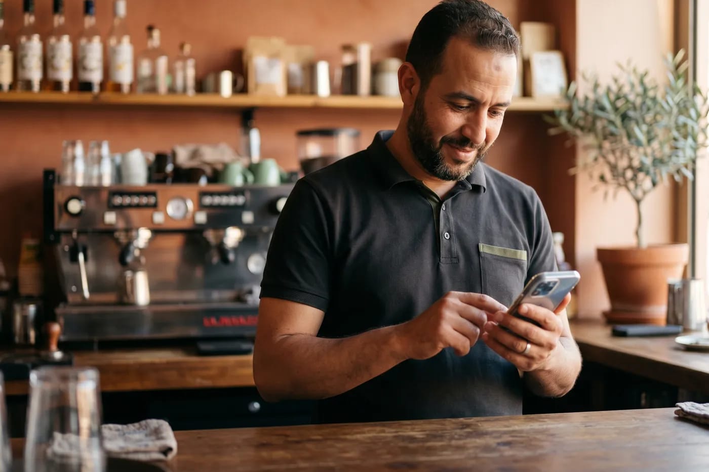 Un cafetier consulte son téléphone derrière son comptoir