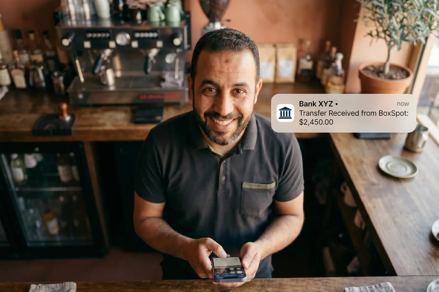 Un commerçant souriant reçoit un virement BoxSpot sur son téléphone