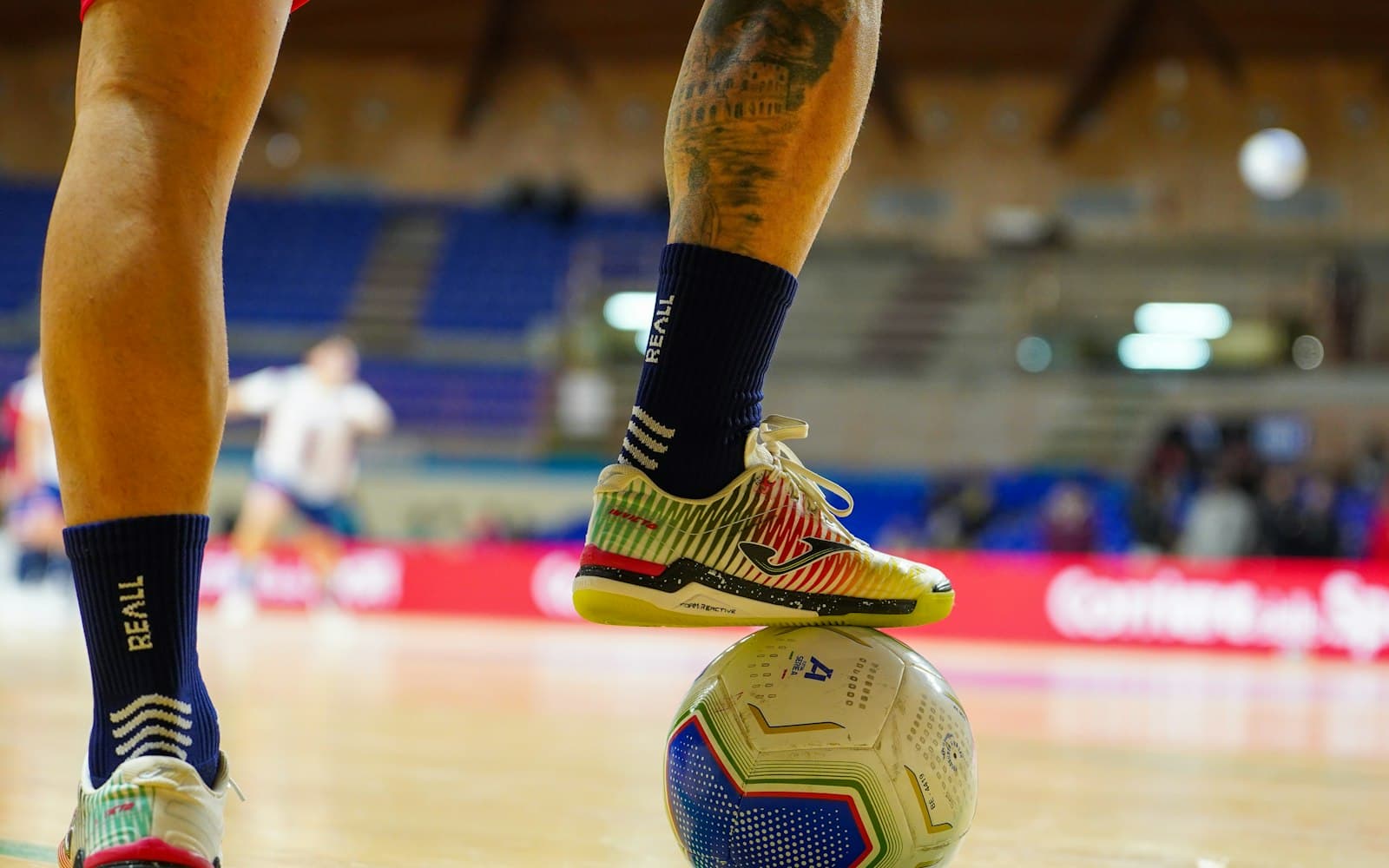 Joueur de futsal, le pied sur le ballon, dans une salle
