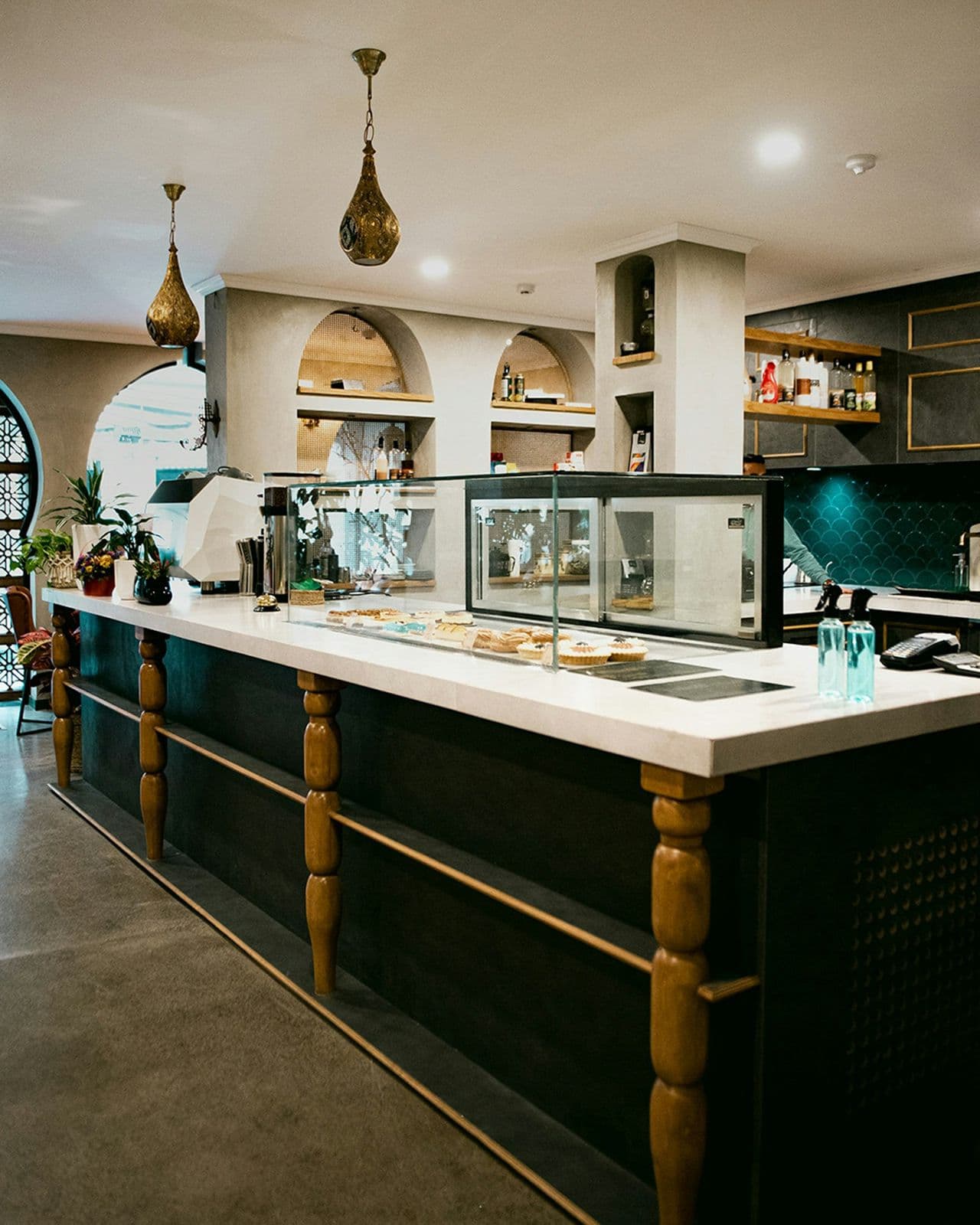 Comptoir de café avec une vitrine de pâtisseries et des suspensions dorées