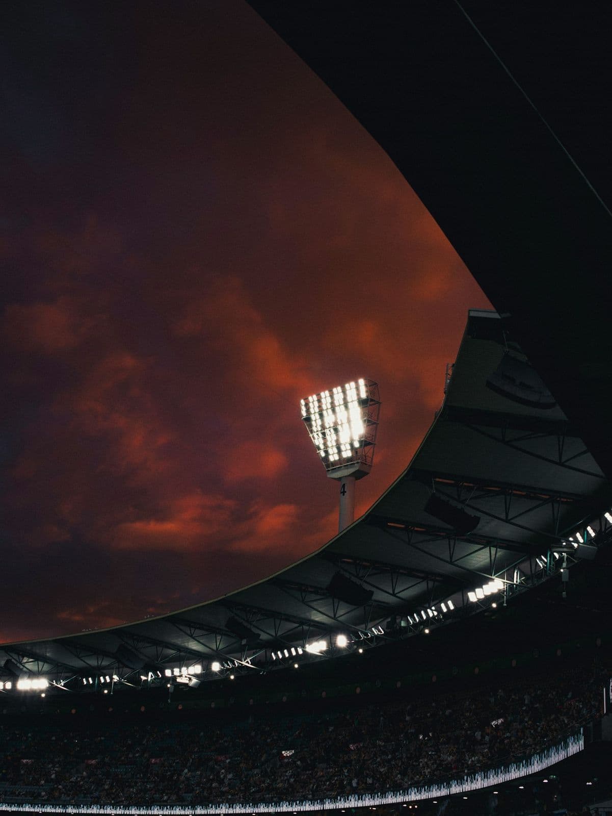 Un projecteur allumé et le bord du toit d'une tribune de grand stade, sous un ciel rouge au crépuscule. Photo d'illustration, ce n'est pas le stade Prince Moulay Abdellah.